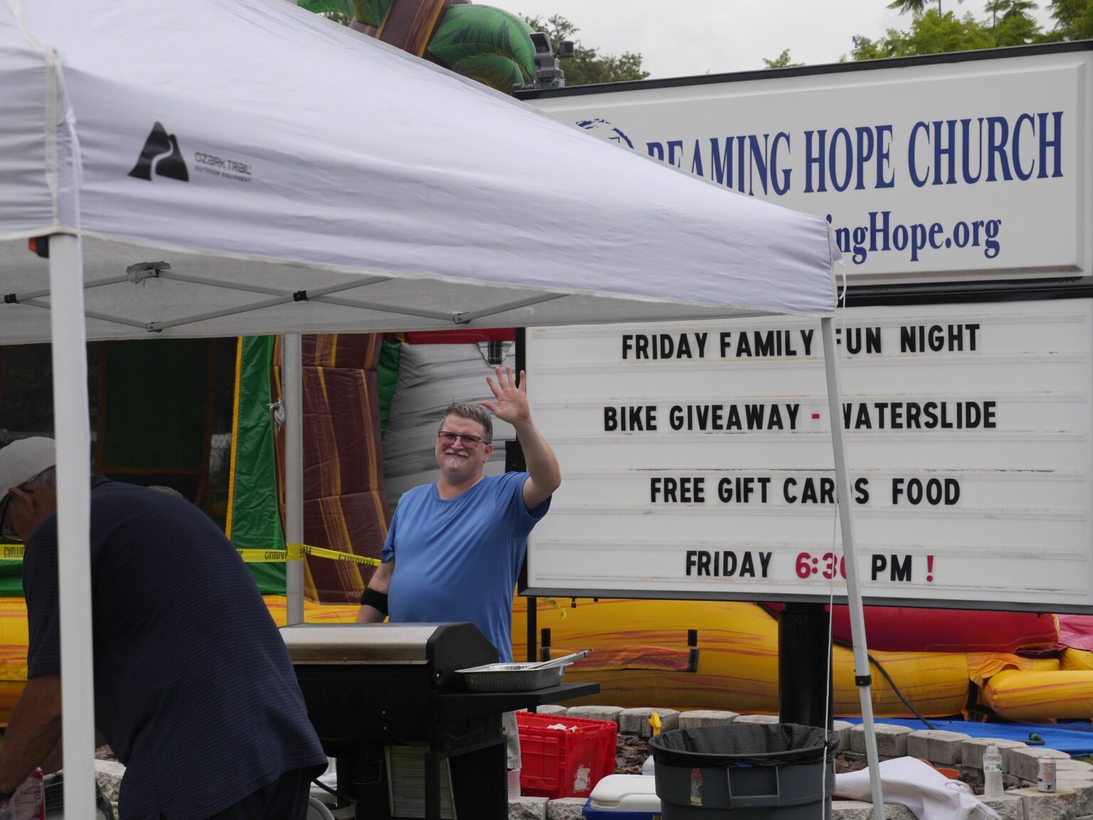 Man waving near church marquee and tent
